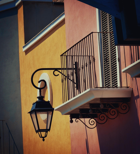 Palazzina colorata con balcone e lampione in ferro battuto.
