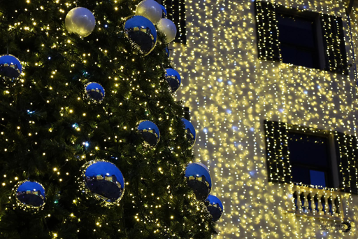 Foto di un particolare di un albero di natale con sfondo di palazzo decorato con luci di natale