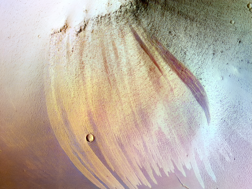 Le striature di versante sono comuni nelle regioni tropicali di Marte. Un tempo si pensava fossero causate da acqua scorrente, ma la maggior parte degli scienziati ora ritiene che si tratti di valanghe di polvere. Di solito sono più scure dell’ambiente circostante e spesso si allargano a ventaglio lungo il pendio. Ciò suggerisce che il sedimento di polvere sia appiccicoso, così che la valanga si allarga mentre scivola verso il basso.

È noto che le striature di versante sbiadiscono nel tempo, ma quelle in questo sito di monitoraggio in Arabia Terra vanno oltre. Qui, le vecchie striature di versante sembrano essere più chiare del terreno circostante. Un confronto tra immagini HiRISE scattate nel 2008 e nel 2019 mostra pochissimi cambiamenti nelle striature scure e chiare.

Nella nostra immagine più recente possiamo vedere tre nuove striature scure. Questi sono i soli cambiamenti individuati tra le centinaia di striature osservate nel sito di monitoraggio, suggerendo che la formazione di nuove striature e lo sbiadimento avvengano su scale temporali di almeno decenni.