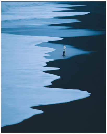 PIc of a man walking on a dark shore.