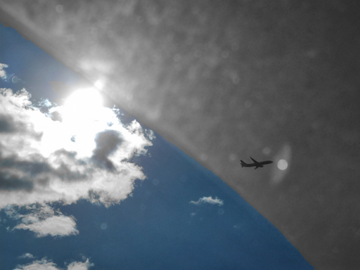 Un piccolo riflesso sull'obiettivo sembra un'apertura verso un altro mondo, un'altra dimensione, e l'aereo in volo sta per attraversarla