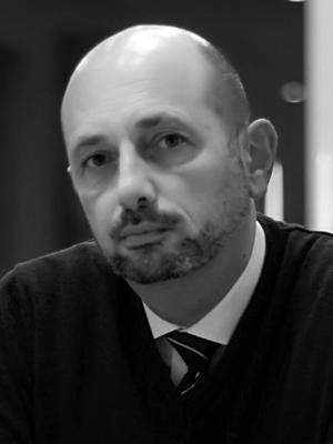 Ritratto fotografico in bianco e nero del Pallavicini. Uomo di mezza età, calvo con baffi e pizzetto, indossa un maglione scollato a V da cui si vedono cravatta regimental e camicia bianca. Lo sguardo è verso l'obiettivo, sereno ma non sorridente