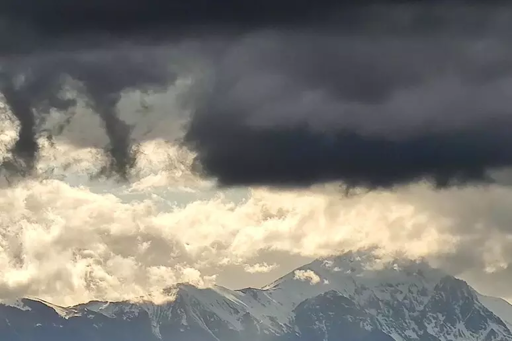 Paesaggi montano di tipo alpino con grandi nuvole nere che incombono sulle cime dei rilievi.