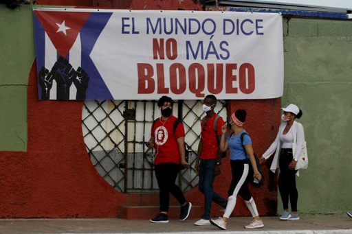 Jóvenes cubanos caminan junto a un cartel alusivo al bloqueo estadounidense contra la nación caribeña  durante una actividad contra el bloqueo de Estados Unidos contra la nación cubana, convocada por la Unión de Jóvenes Comunistas de Cuba (UJC) coincidiendo con las jornadas mundiales de solidaridad con la Isla, en la occidental provincia Matanzas, Cuba. 27 de junio de 2021.Foto: Jorge Luis Baños/IPS