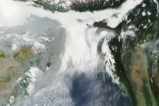 Questa immagine mostra nubi basse sul delta nella mattina del 6 gennaio, riprese dallo strumento MODIS (Moderate Resolution Imaging Spectroradiometer) a bordo del satellite Terra della NASA. La nebbia densa, in particolare la nebbia da irraggiamento, è comune in questo periodo dell’anno: si forma quando le temperature al suolo sono basse, i venti sono deboli e l’umidità è abbondante vicino alla superficie. I servizi meteorologici di Bangladesh e India avevano previsto nebbia da moderata a molto densa sulla regione in quella giornata, nel contesto di un’ondata di freddo in corso.