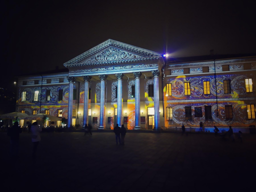 Un edificio storico illuminato da proiezioni artistiche colorate durante la notte.