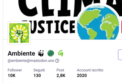 Uno screenshot di un profilo social con uno sfondo che mostra la scritta nera "CLIMA JUSTICE" sovrapposta a un'illustrazione del globo terrestre con continenti verdi e oceani blu. L'immagine del profilo ritrae un pugno bianco alzato all'interno di una forma gialla a raggiera su uno sfondo verde chiaro. Il nome dell'account è "Ambiente", seguito dalle icone di un panda, un cerchio verde e una lettera 'G' verde, con l'handle "[@]ambiente[@]ma "[@]ambiente[@]mastodon.uno". In fondo sono elencati i dati: "Follower 10K", "Seguiti 130", "Post 2,8K" e "Account iscritto 2020".