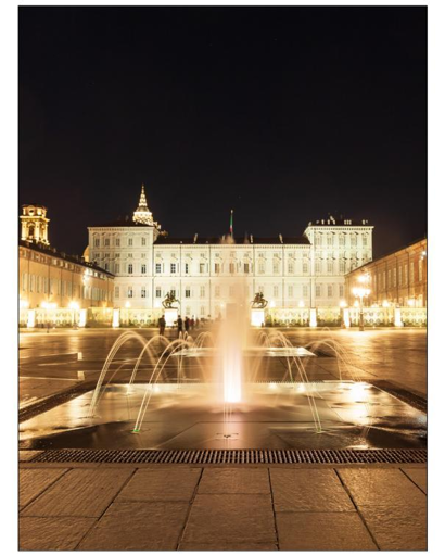 Night view of the square: fountain and castle.
