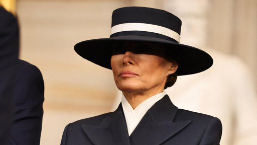 Foto di Melania Trump con cappello che le copre la parte superiore del viso. La foto fa presumere uno stato di tristezza in Melania, che spesso si evince in presenza del marito.