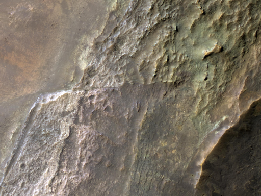 I crateri da impatto sono vere e proprie “sezioni stradali naturali”, che mettono in evidenza gli strati planetari in sezione trasversale. Tuttavia, il violento processo d’impatto può anche alterare gli strati preesistenti.

Un taglio largo circa un chilometro mostra strati inclinati dal bordo del cratere a destra verso il pavimento a sinistra. Un gradiente di colori intensi indica composizioni diverse. In questa zona sono stati rilevati minerali argillosi, e un’interpretazione suggerisce che si siano formati tramite alterazione dovuta agli agenti atmosferici sotto un clima antico più umido, con strati superficiali più alterati dall’acqua rispetto a quelli più profondi.

Un’altra possibile interpretazione è che gli strati con composizioni differenti si siano depositati in epoche diverse, da processi e materiali di origine differenti.

In altre zone, gli strati inferiori appaiono bruscamente spostati lungo una faglia, un fenomeno comune nei crateri da impatto di queste dimensioni (circa 20 chilometri).

Inoltre, gli strati superiori mostrano una distribuzione irregolare dei colori, con alcuni blocchi che potrebbero essere stati espulsi da zone più profonde del cratere durante l’impatto.