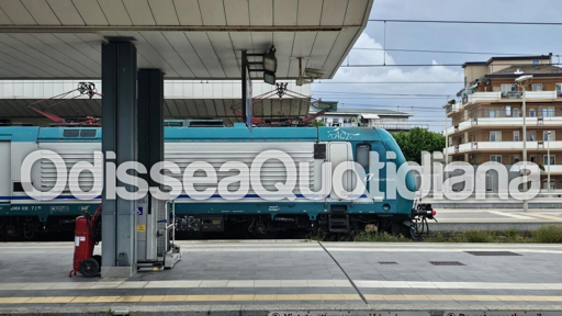 Immagine ferroviaria riferita alla linea FL8 Roma-Nettuno, con un convoglio regionale in prossimità di una stazione o di un tratto ferroviario. Sullo sfondo è rappresentata un’infrastruttura sopraelevata riconducibile a un cavalcaferrovia pedonale. La scena deve richiamare i lavori di demolizione dell’opera e la conseguente sospensione temporanea della circolazione ferroviaria tra Nettuno e Marechiaro.