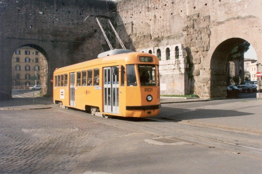 L’immagine mostra un tram della linea 14 in servizio nella rete tranviaria di Roma. Il mezzo è inserito nel contesto urbano della città, con la sede tramviaria e la strada circostante. La fotografia richiama la storia della linea, attiva dal 1958, e il suo collegamento tra il nodo di Termini e il quartiere di Quarticciolo.