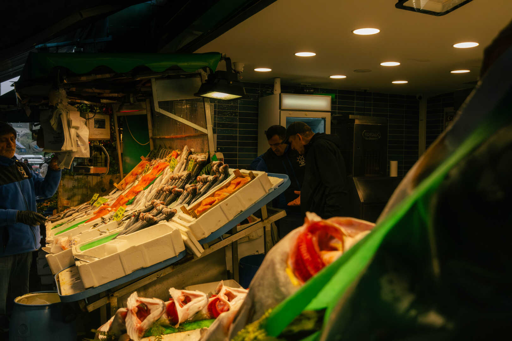 Commercianti di una pescheria di Kadıköy che discutono dietro al bancone, mentre un altro venditore prepara un ordine.